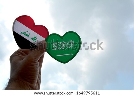Hand holds a heart Shape Iraq and Saudi Arabia flag, love between two countries