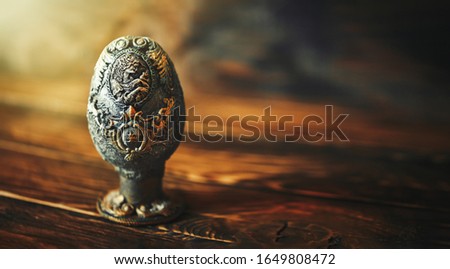 vinage Easter egg decorated with papier-mache hand made, beautiful decorations on egg at stand, picture of woman with bird on egg, on wooden background.