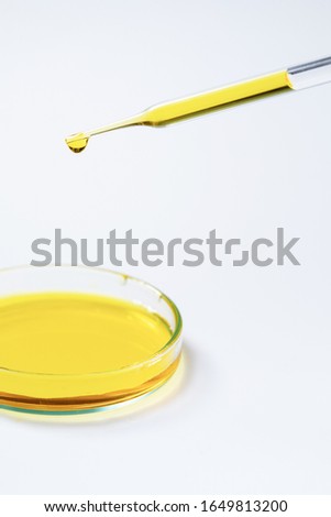 laboratory testing lab dropper with yellow fluid test in petri dish