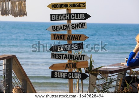 Direction signpost on sea background. Wooden pointer to the beach, Surf club, Shop, ATM.