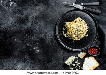 Spaghetti paste with cream blue cheese sauce and walnuts. Italian Home made food. Concept for a tasty, vegetarian dish. Black background. Top view. Copy space