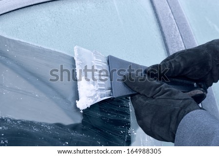 winter driving - scraping ice from a windshield