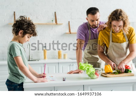 homosexual men cooking near mixed race son drawing with color pencil