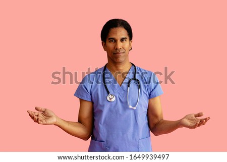 Studio portrait of a friendly male doctor or nurse wearing blue scrubs and stethoscope and arms out
