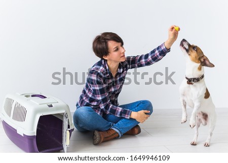 Dog carrying bags and pets owner concept - Attractive cheerful female in plaid shirt holds favourite pet. Happy woman with her jack russell terrier