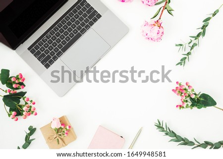Floral frame with laptop, gift, notebook and peony flowers on white background. Top view. Flat lay.