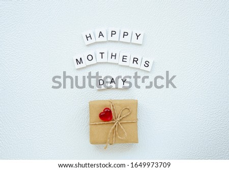 Mothers day gift box with heart and wooden letters made sign Happy mothers day on white background. Top view