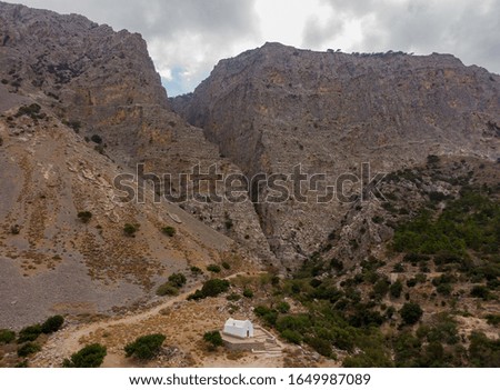 Small white church on the background of a huge rocky gorge in Greece, aerial photo