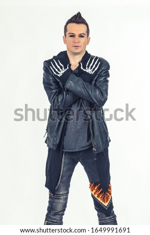 Rebellious musician standing with crossed arms while wearing skeleton gloves.