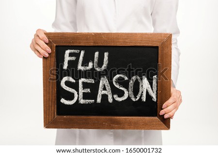 cropped view of doctor holding chalkboard with flu season lettering isolated on white