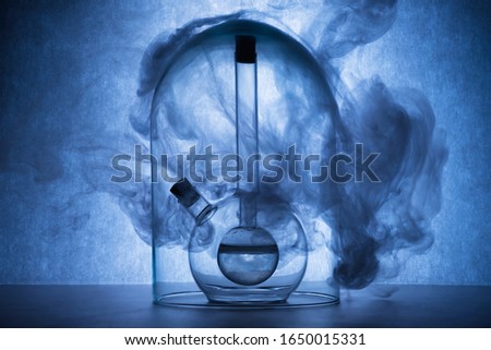 Chemical reaction in glassware on blue background. Flasks with liquid and smoke. Chemical laboratory, science concept. Creative glassware. Copy space