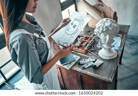 Beautiful asian female painter in art studio. Young talanted artist working.