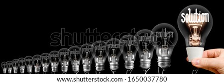 Group of dimmed light bulbs with one of them shining, concept of Problems and Solution, isolated on black background
