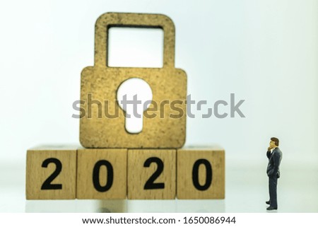 2020 Business, Planning, Insure and Security Concept. Close up of businessman miniature figure people standing and looking to wooden master key lock icon with wood number block with copy space.