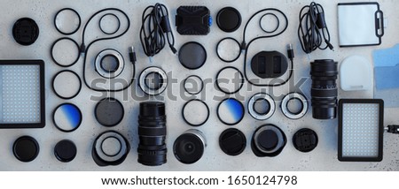 Banner flat lay toned blue equipment for professional photographer on grey. Photo gradient filter, macro rings, polarizing filter, charger, video light with color plates, lens caps all for cameras