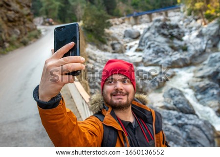 Man taking selfie with cell phone in the nature