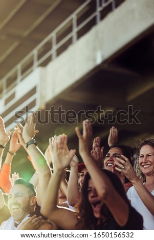 Football supporters clapping and chanting from stadium. Soccer team supporters cheering during a match at stadium. Royalty-Free Stock Photo #1650156532