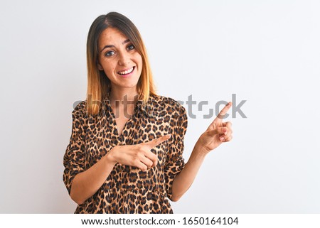 Beautiful redhead woman wearing elegant animal print shirt over isolated background smiling and looking at the camera pointing with two hands and fingers to the side.
