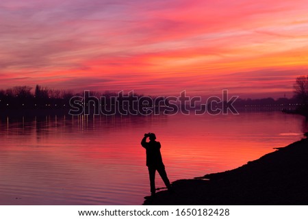 Silhouette of a man taking a photo of a beautiful sunset sky; With copy space