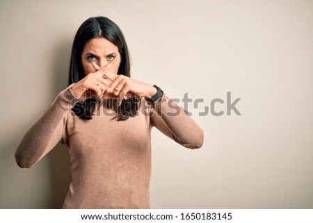 Young brunette woman with blue eyes wearing casual sweater over isolated white background Rejection expression crossing fingers doing negative sign