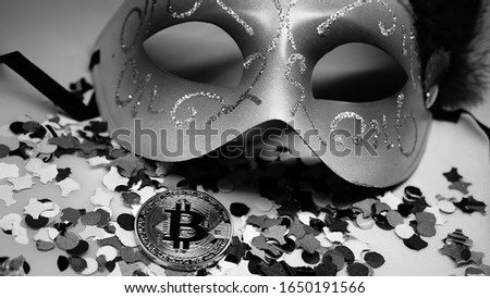 golden bitcoin coin among multicolored paper confetti with carnival mask on white. macro view