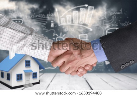Humans shaking hands after signing the contract and house model