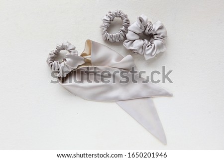 silk Scrunchy isolated on white. Flat lay Hairdressing tools and accessoriesas Color Hair Scrunchies, Elastic Hair Bands, Bobble Sports Scrunchie Hairband. hair scarf fixed on the scrunchie on gray  Royalty-Free Stock Photo #1650201946