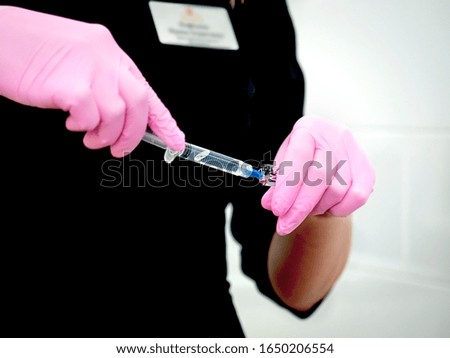 Close-up of hands of young nurse who is dialing medicine into the syringe at the cosmetology clinic