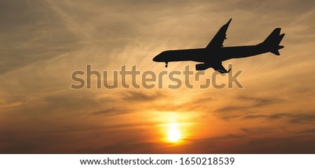 Commercial aircraft making approach in the dramatic sunset light. Landing plane in the dusk