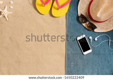 Summer vacation composition. Hat, smartphone and sunglasses on sand background. Harsh light with shadows. Summer background. Border composition made of towel