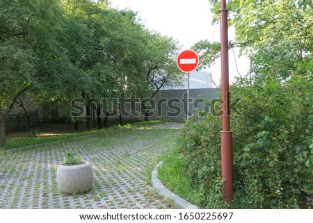 Road sign stop. No entry. High fence, closed territory. Quarantine, epidemic, viral disease. Bright red sign on the background of the overgrown areas.