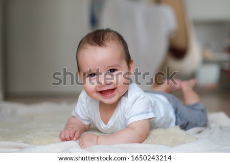 Cute smiling baby boy relaxing at home. Happy infant mixed race Asian-German about 5-6 months old crawling on the floor. Healthy newborn. Royalty-Free Stock Photo #1650243214
