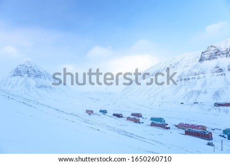 Colorful buildings in Longyearbyen, Svalbard. They are seen from above and against mountains covered in snow.