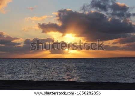 Dramatic skies above the water with a burst of sunset rays through the clouds