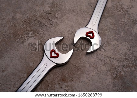 Two wrenches with hearts on a textured background.