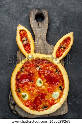 
Easter pizza in the form of a hare with quail eggs on a stone background