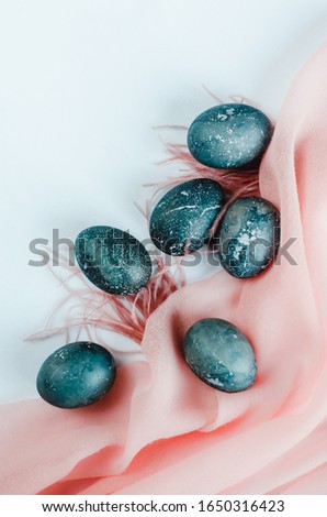 Set of eggs painted in dark grey platinum colour, marble texture, pink material and feathers create delicate composition on white background for Happy Easter greeting card, personal cooking food blog.