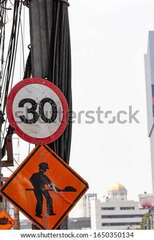 Speed limit sign with construction sign underneath, implying that a car can drive only 30kilometers per hour due to construction site ahead, showing inconvenience and danger on the road.
