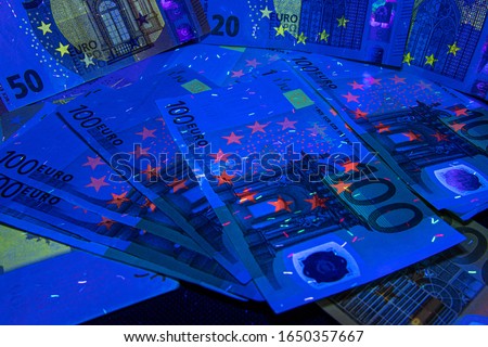 100, 200, 500 euro paper currency under UV light. Verifying the authenticity.