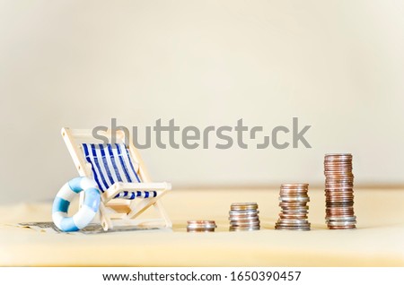 Miniature Beach Chair with Increasing Stacks of Coins Royalty-Free Stock Photo #1650390457