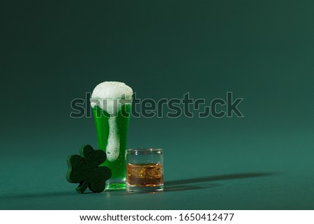 St. Patrick's Pint of Beer and Scotch Whiskey with Wood Four Leaf Clover on a Green Background