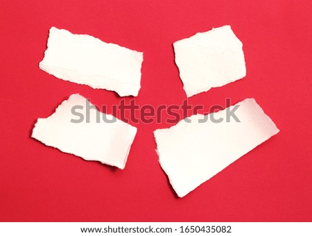 pieces of torn paper on red background. copy space