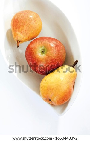 Red and yellow fruit, apple and two pears in a fruit bowl