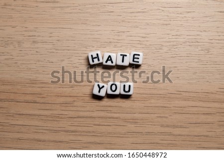 Word HATE YOU in white cubes on light wooden background for your design templates