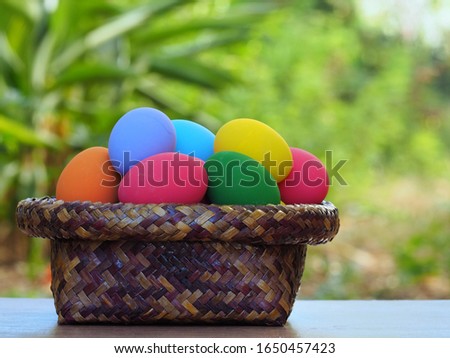 Colorful Easter eggs in the basket on wood table and nature blur background.