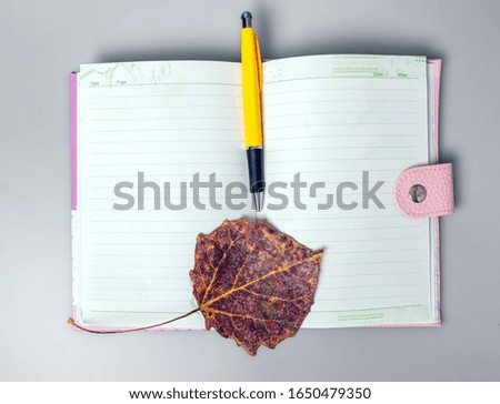 The dried sheet and pen lie on an open notebook. Notebook for notes. Office. School supplies. Place for text. View from above.