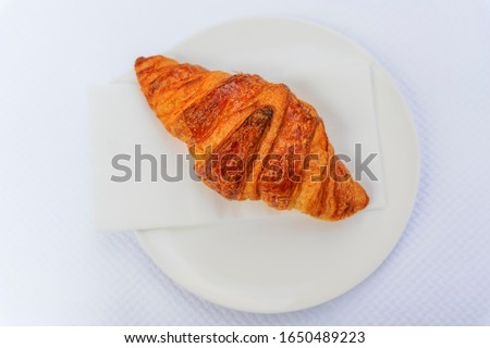 Freshly baked French croissant on a plate at breakfast on a bakery cafe table in Nice, France, flat lay top down view on white textured background