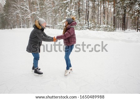 Couple man and woman on ice skating rink in winter