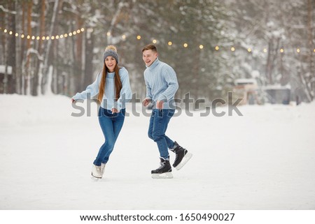 Couple man and woman dancing on ice skating rink in winter.