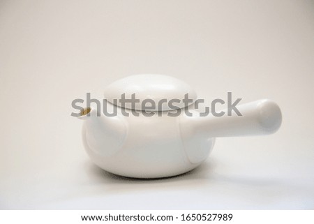 A white Chinese teapot in front of a white background